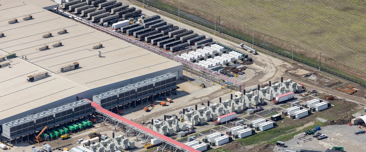An aerial view of SpaceXAI's Colossus datacenter in Memphis. A very large building and a number of smaller connected ones supplying energy and water can be seen.
